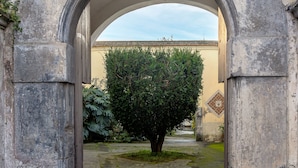 An arched stone gateway leading to a courtyard with a tree and a building in the background. - SMALL COURT MAISON (Piano di Sorrento)