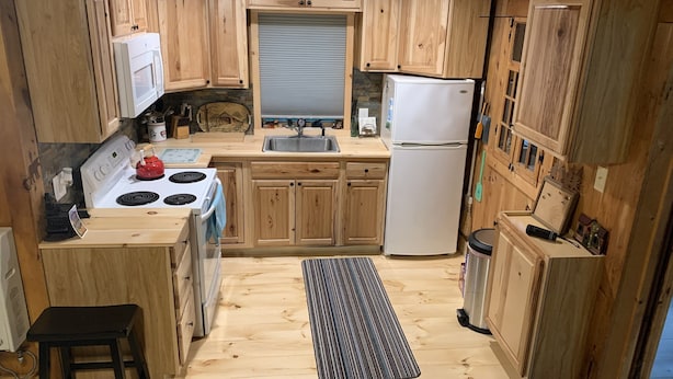 A compact kitchen with wooden cabinets, a white stove, a sink, and a refrigerator. - Cozy cottage (Lunenburg)
