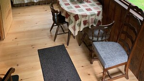 A cozy cabin interior with a wooden bench, a table with a quilted tablecloth, and large windows offering a view of the forest. - Cozy cottage (Lunenburg)