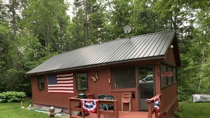 A cabin with a porch, an American flag, and a welcome sign. - Cozy cottage (Lunenburg)