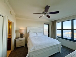 A hotel room with a bed, a nightstand, a lamp, a ceiling fan, and a large window with a view of the sea. - Private Beach, chairs, umbrella & towels included.3 bd 3 bath 2 King Suites.  (Destin)