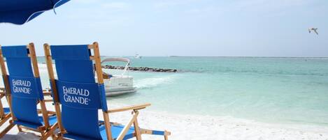 Beach chairs labeled 'Emerald Grande' and a boat on the water.