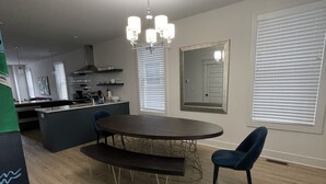 A modern kitchen with a central island, a dining area with a round table and benches, and a large mirror on the wall.