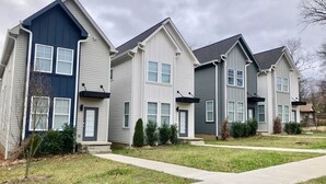 A row of townhouses with a central walkway, each with a front door and windows.