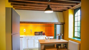 A kitchen with white cabinets, a wooden table, and a window with a view. - So Villa Gouadiere (45) - Heated pool - Basketball - 2h Paris - 30p (Poilly-lez-Gien)