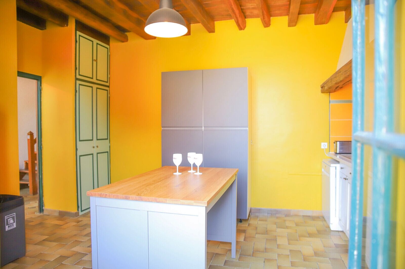 Une pièce avec une table en bois, une armoire blanche et un mur jaune.