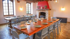 A dining area with multiple tables set for a meal, a stone fireplace, and large windows. - So Villa Gouadiere (45) - Heated pool - Basketball - 2h Paris - 30p (Poilly-lez-Gien)