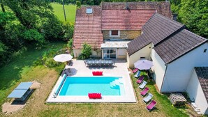 Luchtbeeld van een huis met een zwembad, tuinmeubilair en een terras.