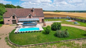 A large house with a swimming pool, outdoor seating, and a fenced garden area.