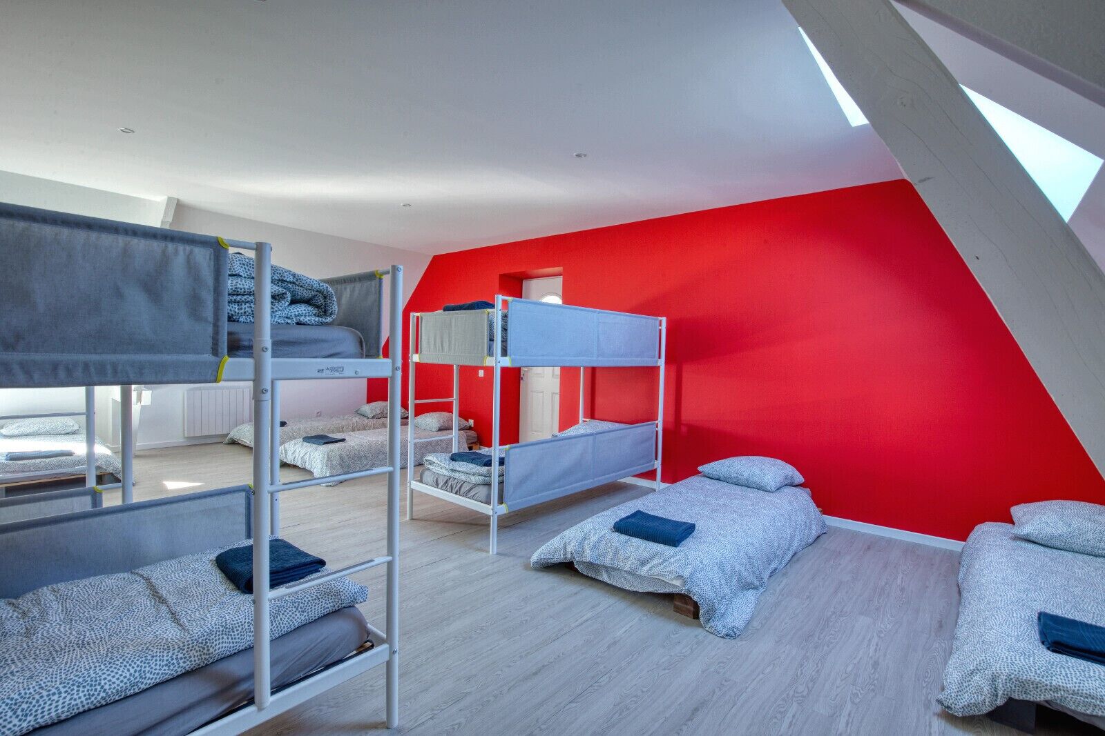 Une chambre de dortoir avec des lits superposés, un mur d’accent rouge et un puits de lumière.