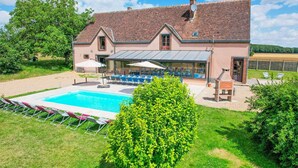 A two-story house with a swimming pool, outdoor seating, and a garden.