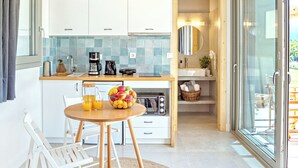 Une cuisine moderne avec des meubles blancs, un plafond en bois et un coin repas comprenant une table ronde et des chaises.