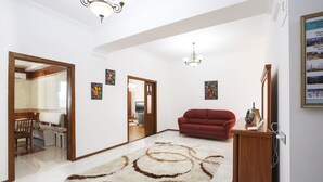 A spacious living room with a red sofa, a wooden cabinet, and a chandelier. - Fountain Square (Baku)