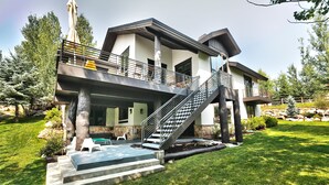 Una casa moderna de dos pisos con un balcón, una escalera y un césped bien cuidado.
