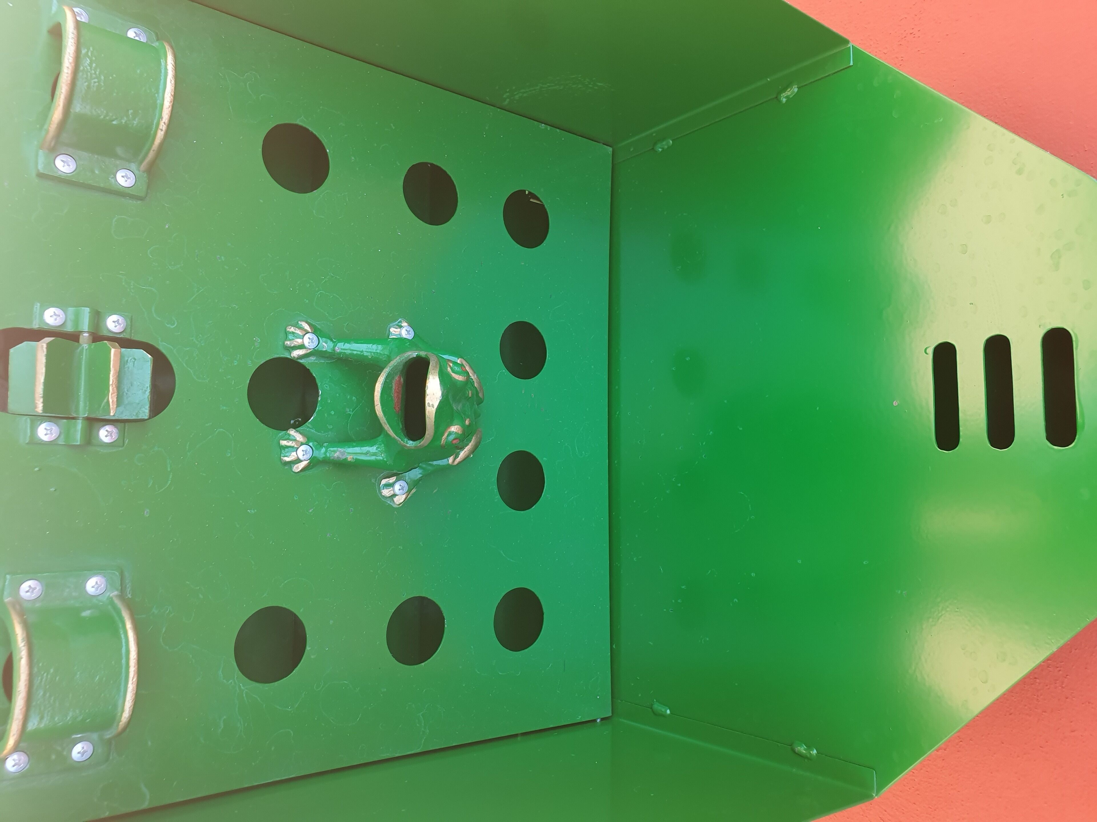 Una estructura metálica verde con múltiples agujeros circulares y un corte rectangular central.