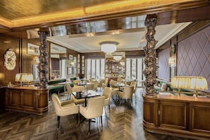 A spacious dining area with high ceilings, ornate columns, and a chandelier. Tables are arranged around a central green seating area. - Hotel-restaurant Erbprinz (Ettlingen)