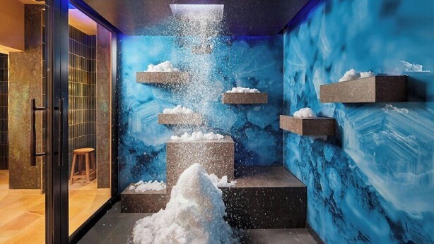 A modern interior with a central water feature, stone platforms, and a blue wall mural. - Hotel-restaurant Erbprinz (Ettlingen)