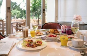 Een ontbijttafel met diverse gerechten, zoals eieren, toast en fruit, plus drankjes en een krant.