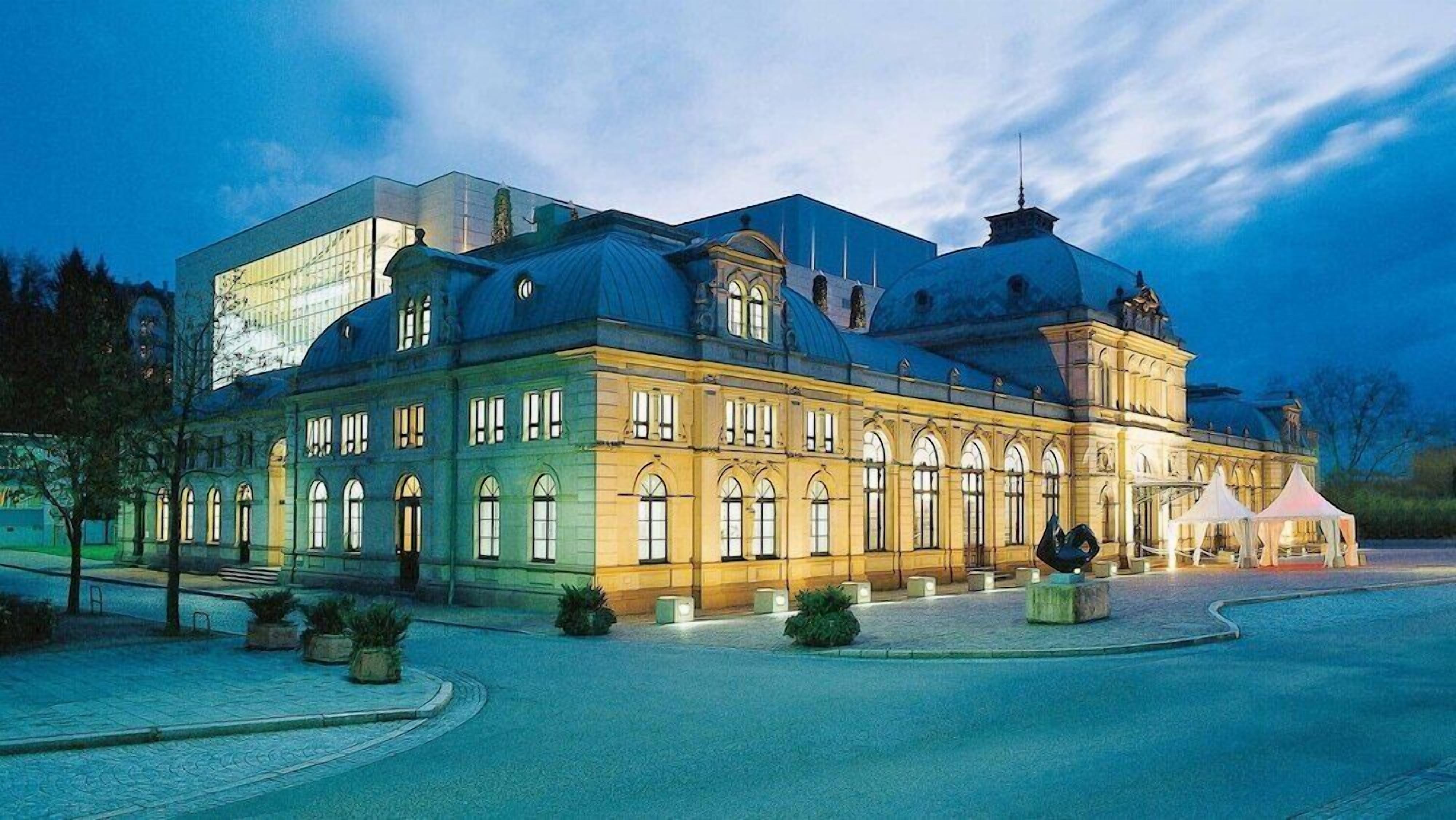 Un grand bâtiment historique, doté d’un dôme imposant et d’une extension moderne en verre.