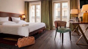 A hotel room with a bed, a chair, a table with a lamp, and a view of buildings through the window. - Hotel-restaurant Erbprinz (Ettlingen)