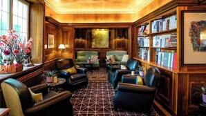 A library with leather chairs, bookshelves, and a patterned floor. - Hotel-restaurant Erbprinz (Ettlingen)