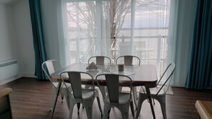Ein Essbereich mit einem rechteckigen Tisch, sechs Stühlen und einem großen Fenster mit Vorhängen.