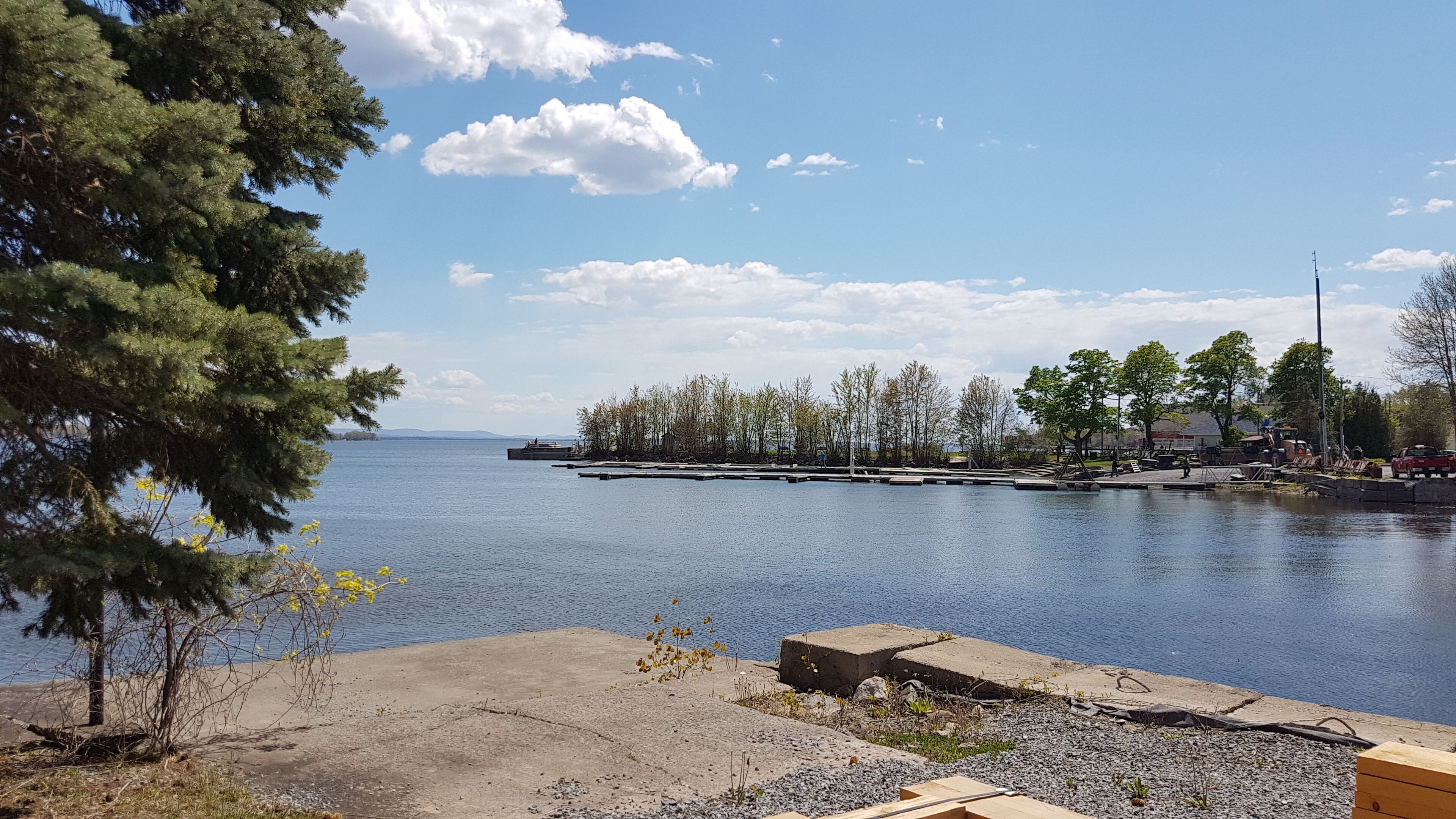 Vista al agua con un muelle, árboles y cielo despejado.
