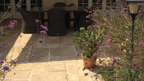 Eine Terrasse mit Tisch, Stühlen, einem Blumentopf und einer Laterne.