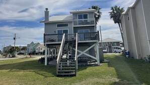 A two-story house with a balcony and a staircase leading to the upper level. - Updated house on lagoon! Quick walk to the beach and beautiful water view! (Gulf Shores)
