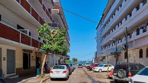 Une rue bordée de voitures garées et d’immeubles des deux côtés.
