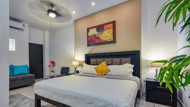 Une chambre d’hôtel moderne équipée d’un grand lit, d’un bureau, d’une chaise, d’un canapé et d’un ventilateur de plafond.