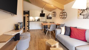 A modern living room with a grey sofa, wooden coffee table, and a dining area with a wooden table and chairs.