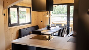 Una cocina moderna con una isla central, paredes de madera y ventanas amplias.