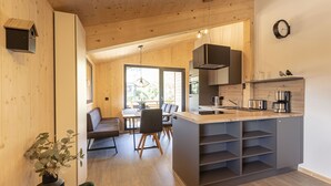 Una cocina moderna con una isla central, suelo de madera y un área de comedor con sofá y sillas.