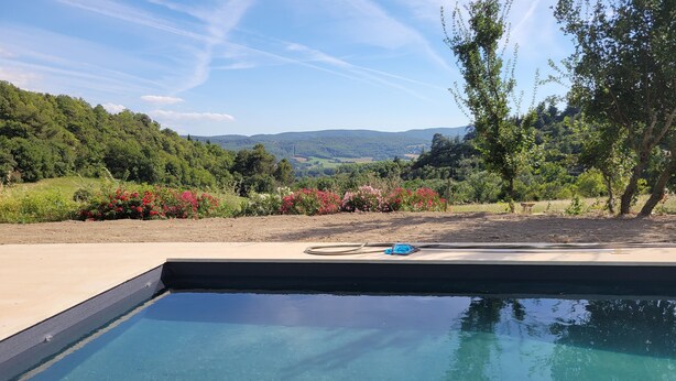 A swimming pool with clear water, surrounded by a landscaped garden with various plants and flowers. - Independent apartment, - 4 people (Reillanne)