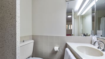 A bathroom with a toilet, sink, and mirror.