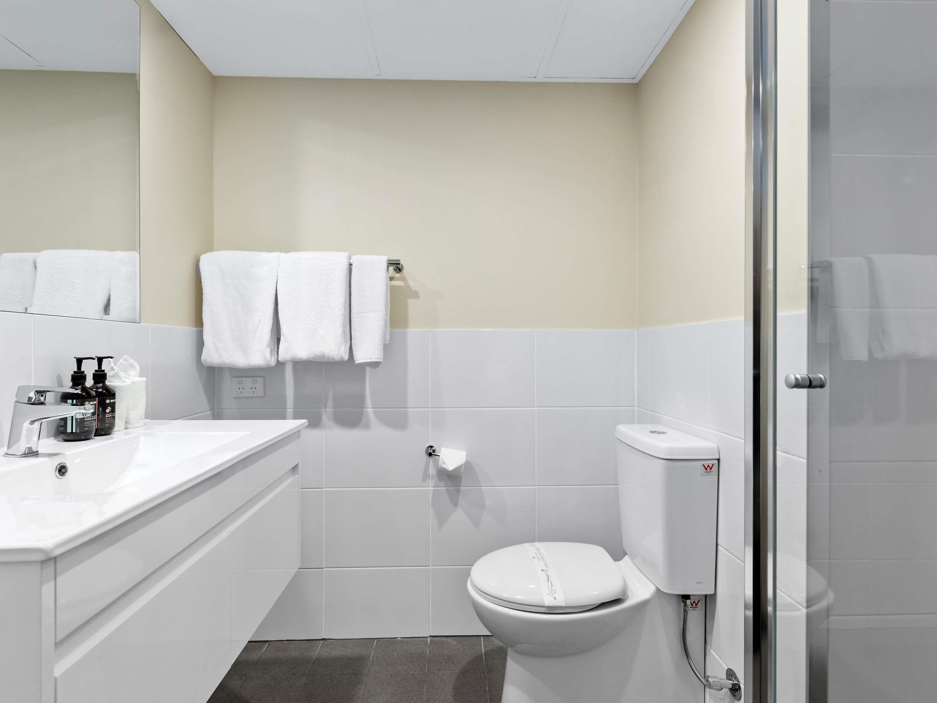 A modern bathroom with a white sink, toilet, and shower.