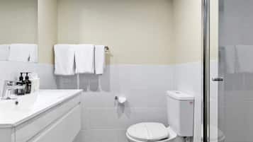 A modern bathroom with a white sink, toilet, and shower.