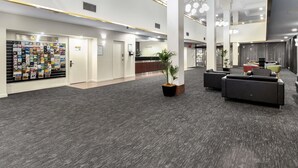A spacious lobby with a reception desk, a display of brochures, and a seating area with sofas. - Breakfree North Adelaide (North Adelaide)