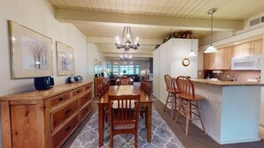 A spacious kitchen with wooden cabinetry, a dining area with a large table and chairs, and a central island with a sink.