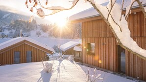 A wooden cabin with a snow-covered roof and a clear view of the surrounding snowy landscape.