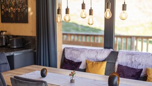 A dining area with a wooden table, chairs, and hanging light bulbs.