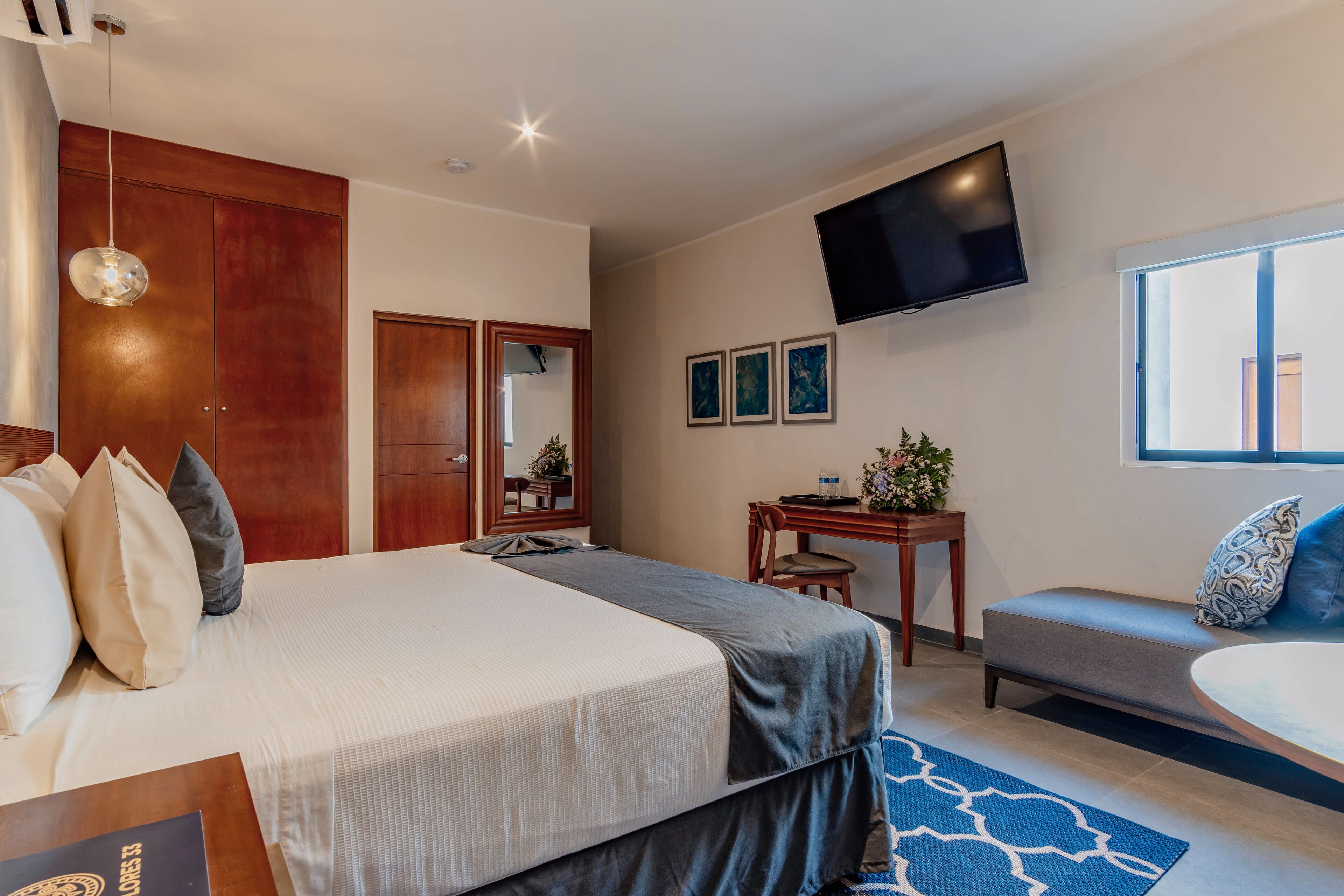 Habitación de hotel con una cama grande, un escritorio, un sofá, un televisor y una ventana.