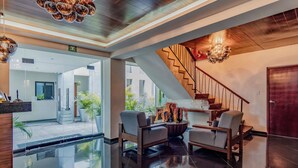A modern lobby with a glass reception desk, a staircase, and seating area with a view of the outdoors. - Youssef Exceptionnel Merida (Mérida)