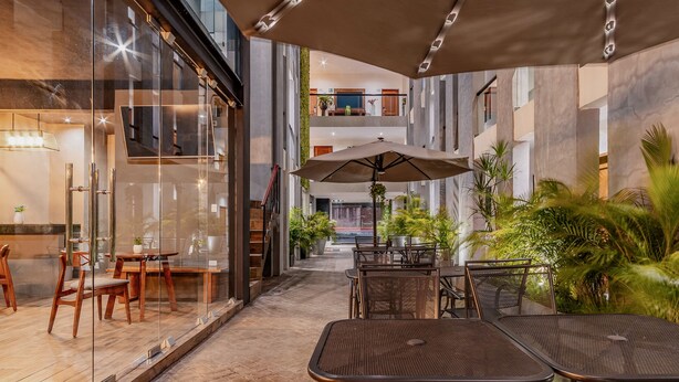 An indoor/outdoor dining area with glass walls, metal tables, and chairs, and a large umbrella. - Youssef Exceptionnel Merida (Mérida)