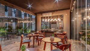 A modern restaurant with round tables and wooden chairs, large windows, and hanging pendant lights. - Youssef Exceptionnel Merida (Mérida)
