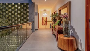 A modern hallway with a glass railing, a wooden bench, a vase with flowers, and a number sign on the wall. - Youssef Exceptionnel Merida (Mérida)