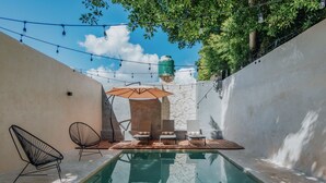 A pool area with lounge chairs, an umbrella, and string lights. - Youssef Exceptionnel Merida (Mérida)