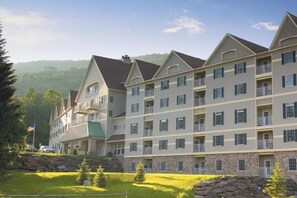 A multi-story hotel with a stone facade, balconies, and a view of the surrounding landscape.