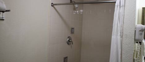 Una ducha con puerta de vidrio, un perchero y un cabezal de ducha.